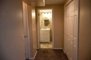 Corridor with light carpet, a sink, and baseboards
