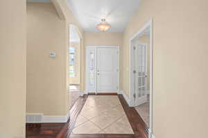 Entrance foyer with tile patterned floors, arched walkways, visible vents, and baseboards