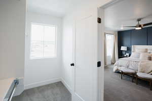 Carpeted bedroom with baseboards and multiple windows