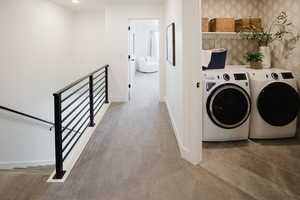 Clothes washing area with laundry area, washing machine and clothes dryer, light colored carpet, and baseboards