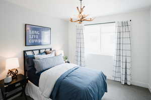 Carpeted bedroom with baseboards and a notable chandelier