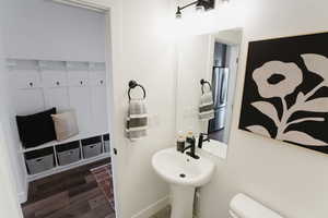 Half bathroom with toilet, wood finished floors, and baseboards