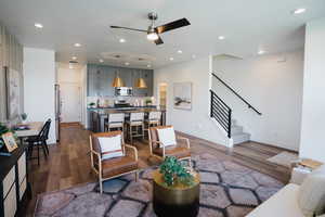 Living room featuring recessed lighting, ceiling fan, dark wood finished floors, and stairs