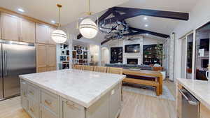 Kitchen featuring light wood-style floors, vaulted ceiling with beams, a ceiling fan, and stainless steel built in fridge