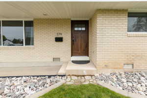 Entrance to property featuring crawl space and brick siding