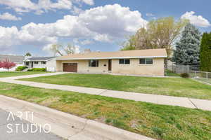 Single story home featuring brick siding, fence, driveway, a front lawn, and an attached garage