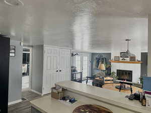 Living area with dark wood finished floors, baseboards, a brick fireplace, a textured ceiling, and french doors
