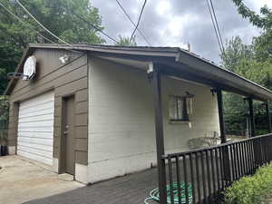 View of home's exterior featuring concrete block siding, a deck, and an outdoor structure