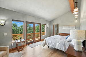 Bedroom with vaulted ceiling, access to outside, and light wood finished floors