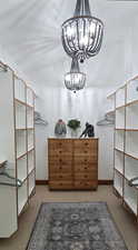 Walk in closet with a chandelier and carpet