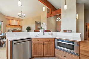 Kitchen featuring appliances with stainless steel finishes, a chandelier, open floor plan, light countertops, and high vaulted ceiling