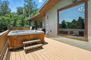 Wooden terrace with a hot tub and view of scattered trees