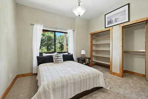 Carpeted bedroom with multiple closets and baseboards