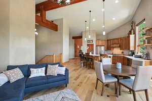 Dining space with high vaulted ceiling and light wood-style floors