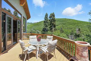 Deck with a view of trees and outdoor dining space