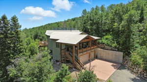 View of front of property with a forest view, driveway, and stucco siding