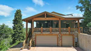 View of front of property with stairway, covered porch, a garage, concrete driveway, and stone siding