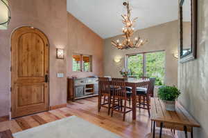 Dining area with hickory wood flooring, high vaulted ceiling, an inviting antler chandelier, and a wealth of natural light