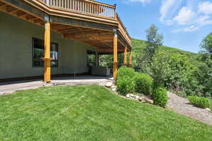 View of grassy yard featuring a patio and a deck