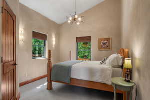 Bedroom with a chandelier, multiple windows, vaulted ceiling, and carpet floors