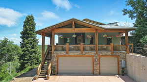 View of front of house featuring covered porch, stairs, a garage, driveway, and stone siding