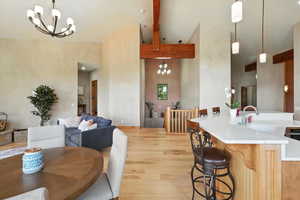Dining space with a chandelier, light wood-style floors, high vaulted ceiling, and beam ceiling