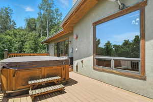 Wooden terrace featuring a hot tub and view of wooded area
