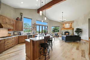 Kitchen featuring stainless steel gas stovetop, custom exhaust hood, light wood-type flooring, beam ceiling, and light countertops