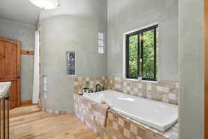 Full bathroom featuring wood finished floors, a garden tub, and vanity
