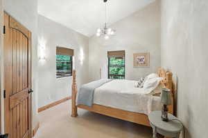 Carpeted bedroom with lofted ceiling, multiple windows, and a chandelier