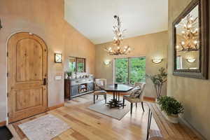Dining room featuring a chandelier, high vaulted ceiling, and light wood finished floors