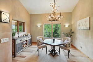 Dining space featuring light wood finished floors, a chandelier, and a high ceiling