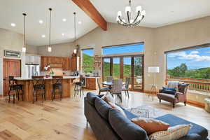 Living area with high vaulted ceiling, light wood-style floors, beam ceiling, a chandelier, and recessed lighting