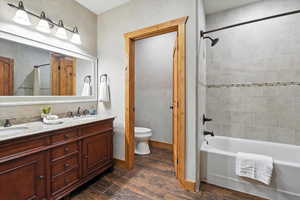 Full bathroom featuring wood finished floors, double vanity, and washtub / shower combination