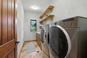 Laundry area with independent washer and dryer and light wood-style floors