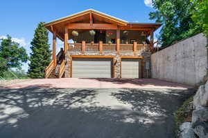 View of front of house featuring an attached, heated garage, heated valet pad, asphalt driveway, and stone accents.