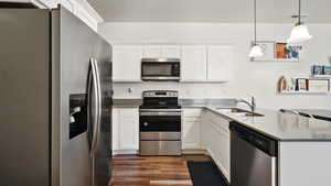 Kitchen featuring visible vents, a sink, a peninsula, stainless steel appliances, and dark wood-type flooring