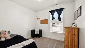 Carpeted bedroom featuring baseboards and visible vents