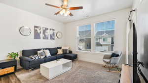 Living area featuring visible vents, baseboards, and a ceiling fan