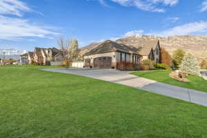 View of front of home featuring an attached garage, concrete driveway, stucco siding, and a front lawn