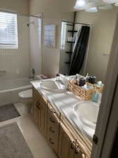 Full bathroom with toilet, a sink, double vanity, and tile patterned flooring