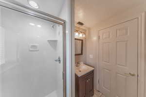 Basment bathroom with a shower stall, vanity, and tile floors