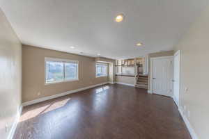 Unfurnished living room with baseboards, and dark wood-style floors