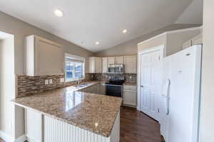 Kitchen featuring stainless steel microwave, electric range, freestanding refrigerator, lofted ceiling, granit counter tops