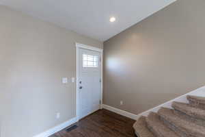 Entrance foyer featuring dark wood-type flooring, recessed lighting, stairway, and baseboards