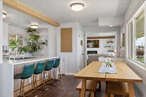 Dining room featuring dark wood-style flooring, kitchen bar