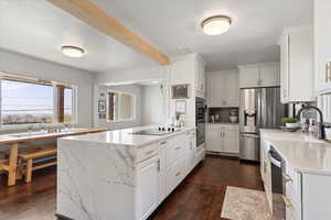 Kitchen featuring dark wood-style floors, white cabinets, decorative backsplash, and stainless steel appliances