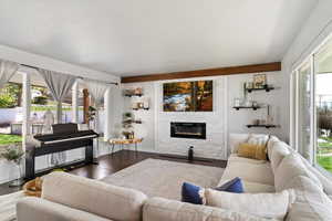 Living room with plenty of natural light, a fireplace, and dark wood finished floors, decorative beam