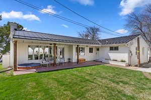 Back of property with board and batten siding, a patio area, and metal roof