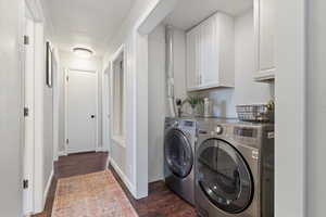 Laundry area with dark wood-style flooring, independent washer and dryer, baseboards, and cabinet space